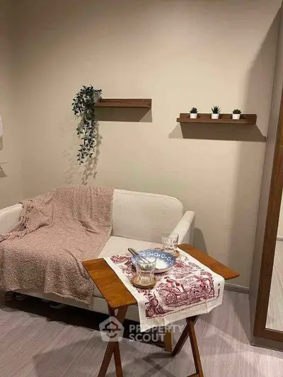 Cozy living room with white sofa, wooden table, and decorative shelves.
