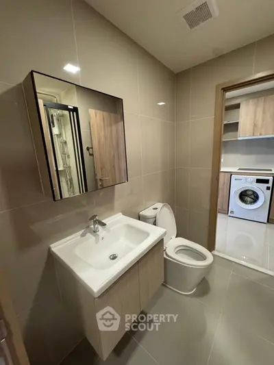 Modern bathroom with sleek fixtures and adjacent laundry area