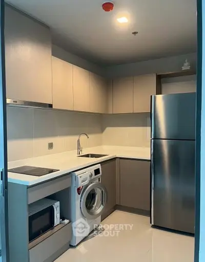 Modern kitchen with sleek cabinets, stainless steel fridge, and built-in appliances in a compact layout.