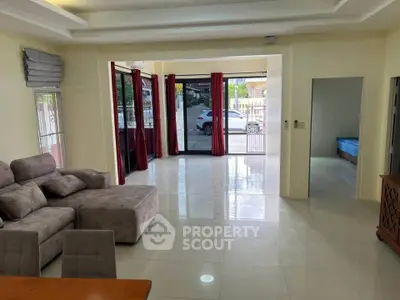 Spacious living room with modern furniture and large windows offering natural light and outdoor view.