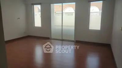 Spacious empty room with wooden flooring and large windows