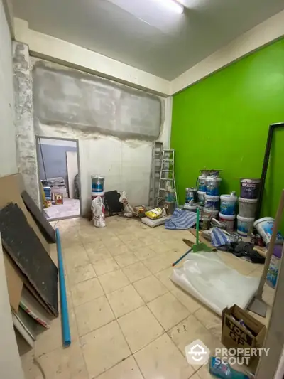 Spacious room under renovation with bright green accent wall and construction materials.