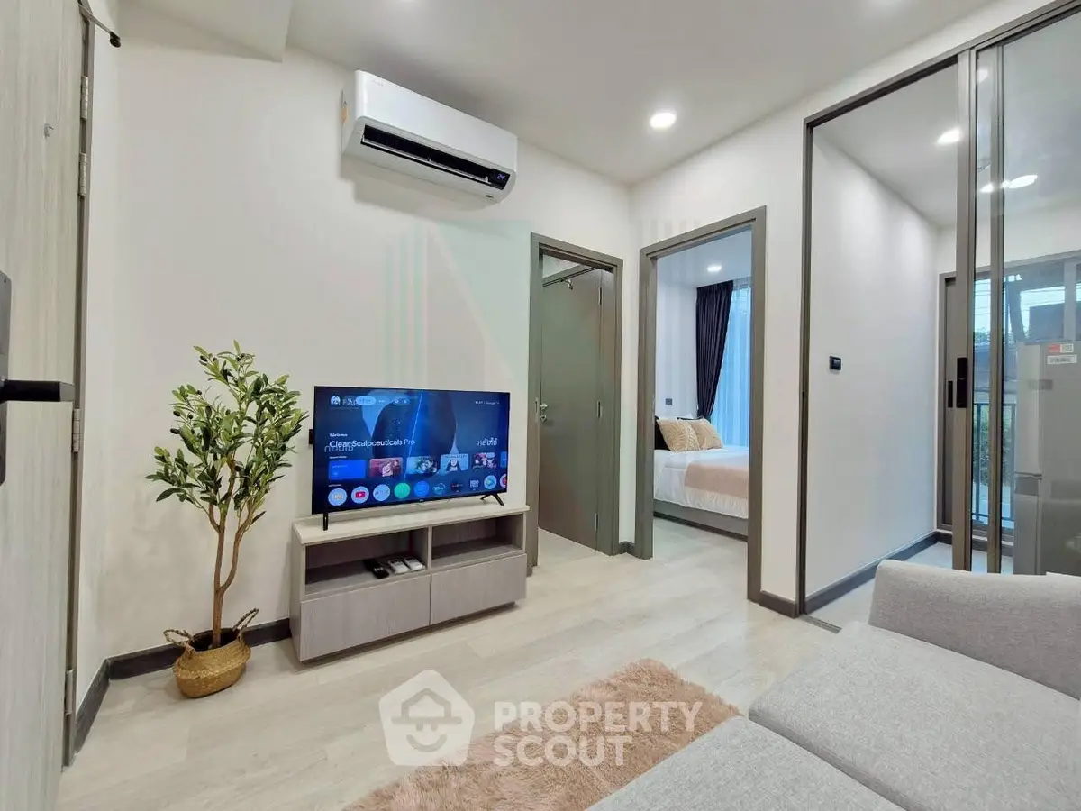 Modern living room with air conditioning and TV, adjacent to a cozy bedroom.