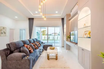 Luxurious living room with plush seating and modern decor, featuring large windows and elegant lighting.