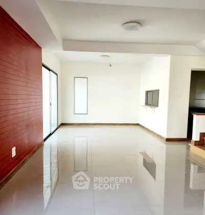 Spacious modern living room with red accent wall and large windows