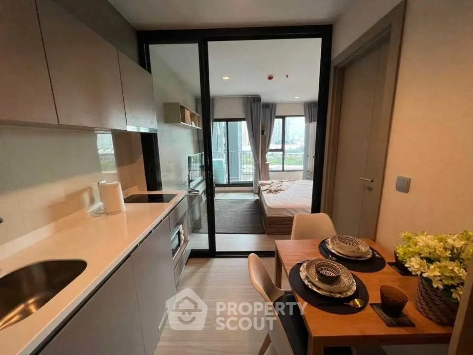 Modern studio apartment with compact kitchen and cozy bedroom, featuring stylish decor and city view.