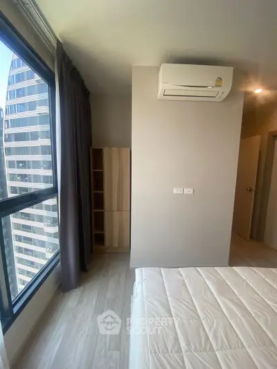 Modern bedroom with large window and air conditioning in high-rise building.