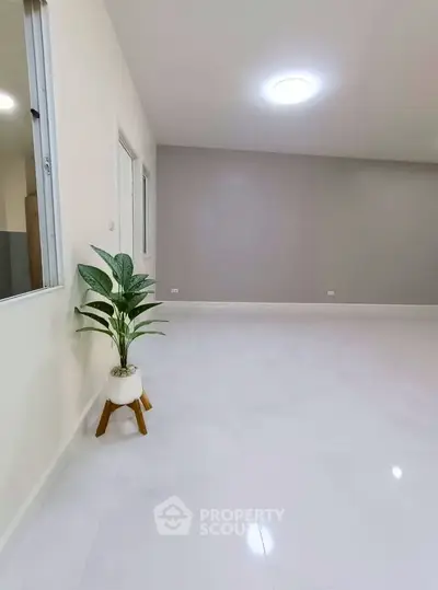 Spacious minimalist living room with sleek white flooring and modern decor.