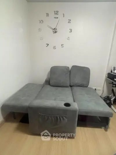 Modern living room with stylish gray sofa and wall clock, perfect for cozy relaxation.