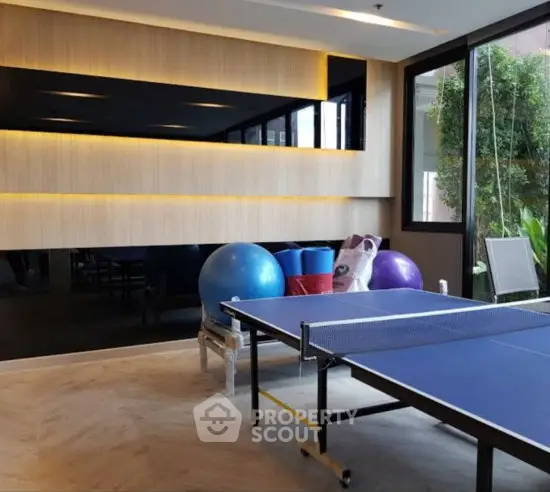 Modern indoor recreational area with ping pong table and exercise equipment in a stylish apartment complex.