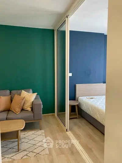 Modern apartment with cozy living room and stylish bedroom separated by glass doors.