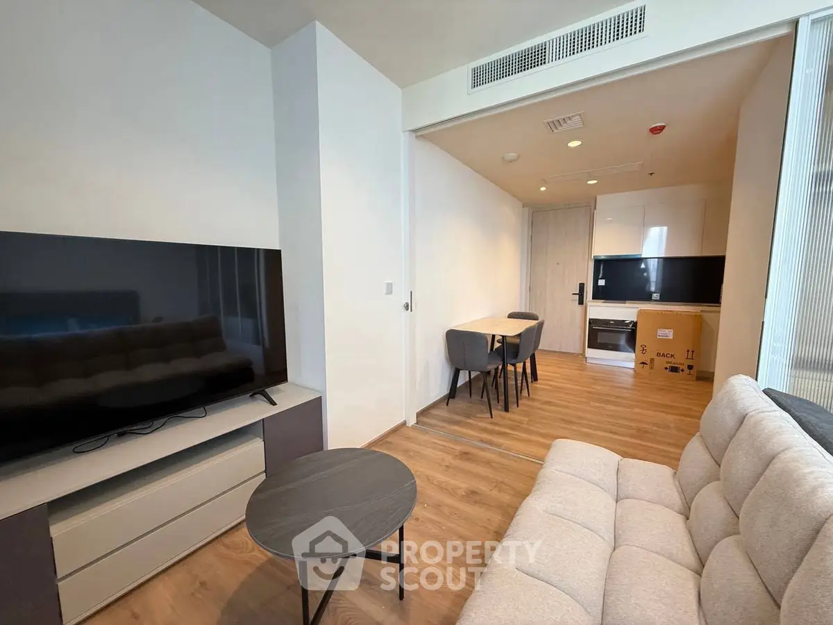 Modern living room with sleek furniture and open kitchen layout in a stylish apartment.