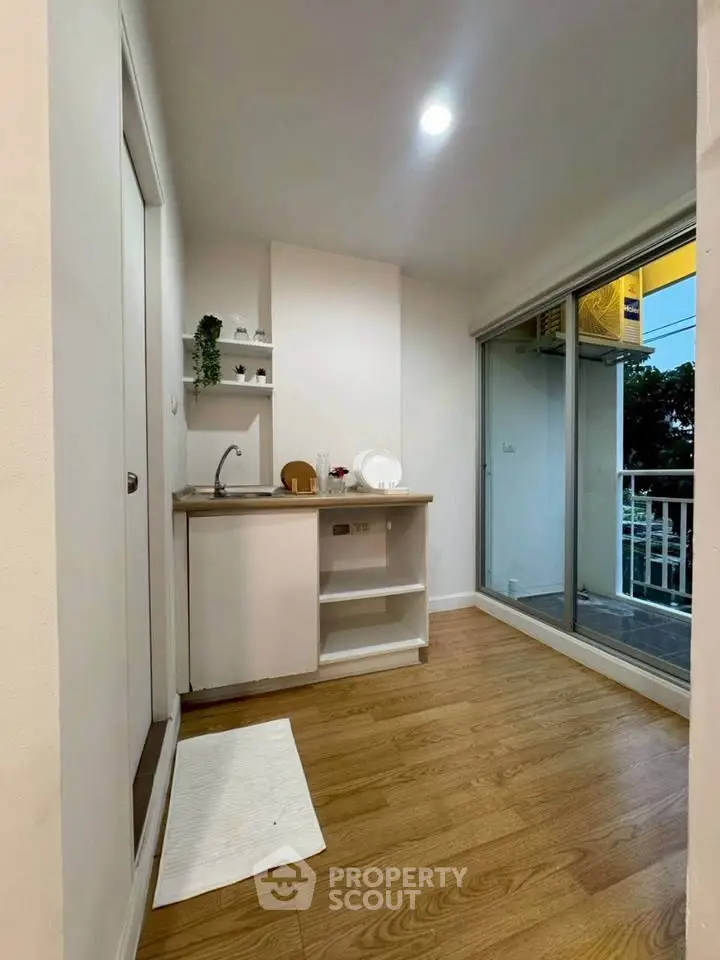 Modern compact kitchen with wooden flooring and balcony access