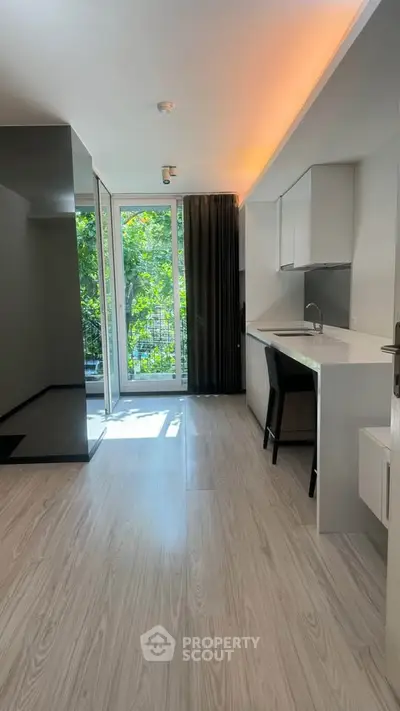 Modern open-layout kitchen with sleek design and large windows offering lush green views.