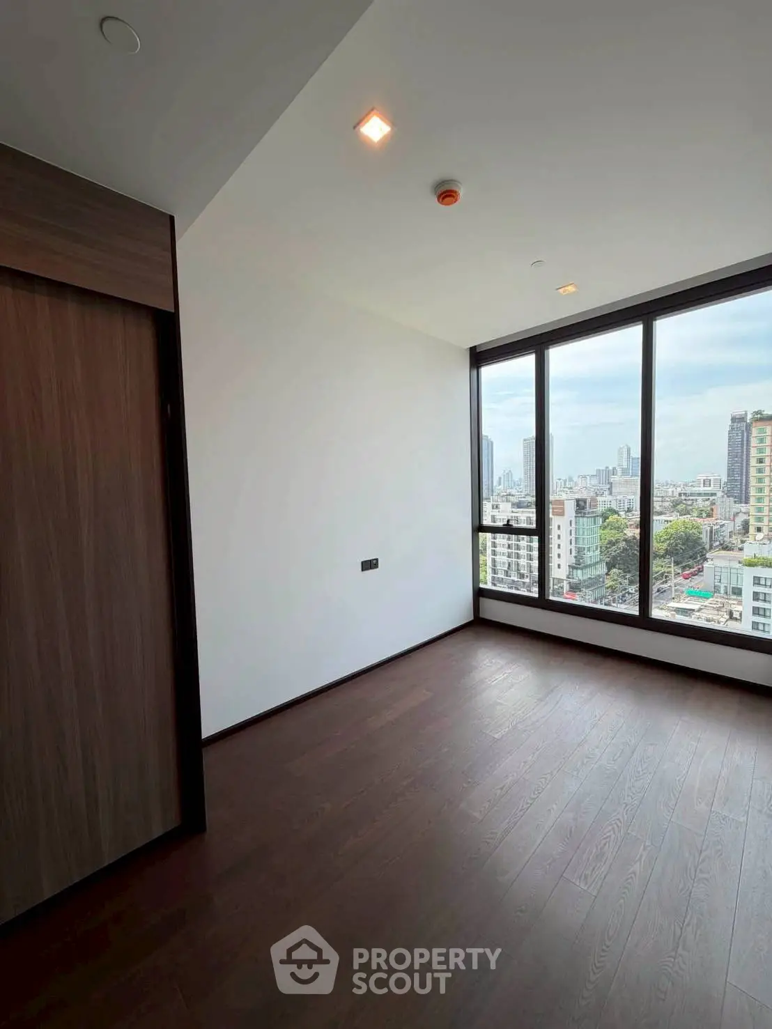 Spacious room with large windows offering stunning city views in a modern high-rise building.