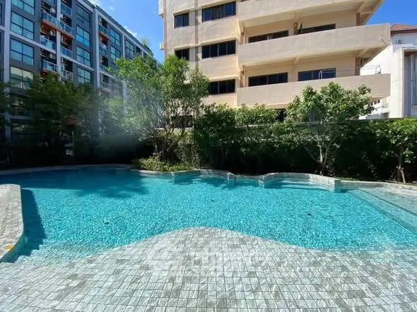 Luxurious residential pool area with crystal-clear water and lush greenery, perfect for relaxation and leisure.