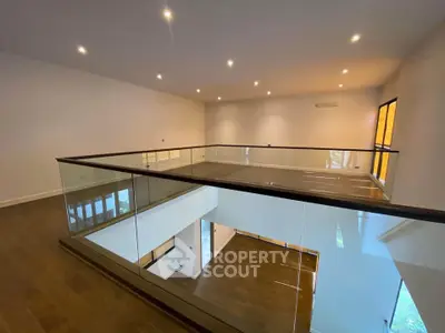 Spacious modern interior with glass railing and wooden flooring, perfect for contemporary living.