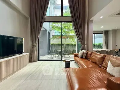 Spacious modern living room with high ceilings and large windows overlooking a private garden.