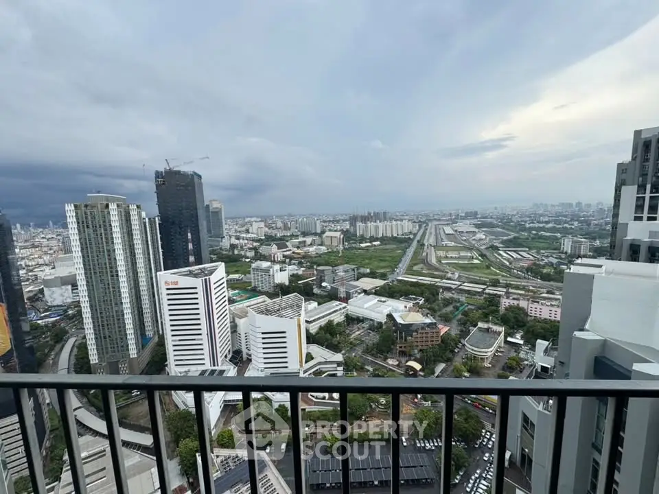 Stunning cityscape view from high-rise balcony overlooking urban skyline and railway tracks.
