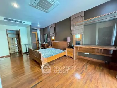 Spacious bedroom with wooden flooring and elegant furniture in a modern home.