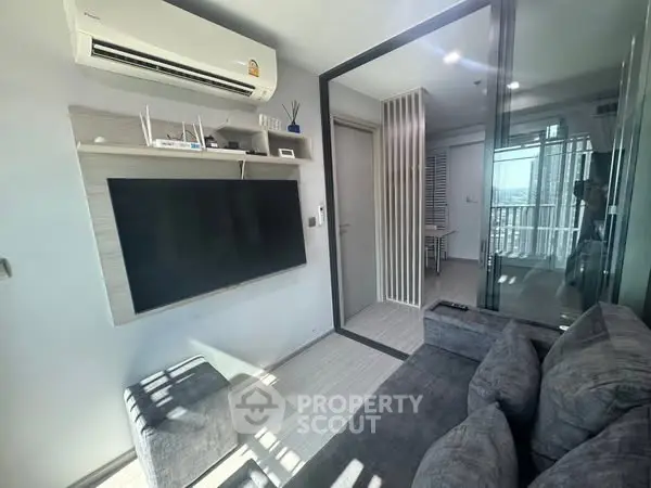 Modern living room with sleek design, featuring a large TV, air conditioning, and stylish decor.