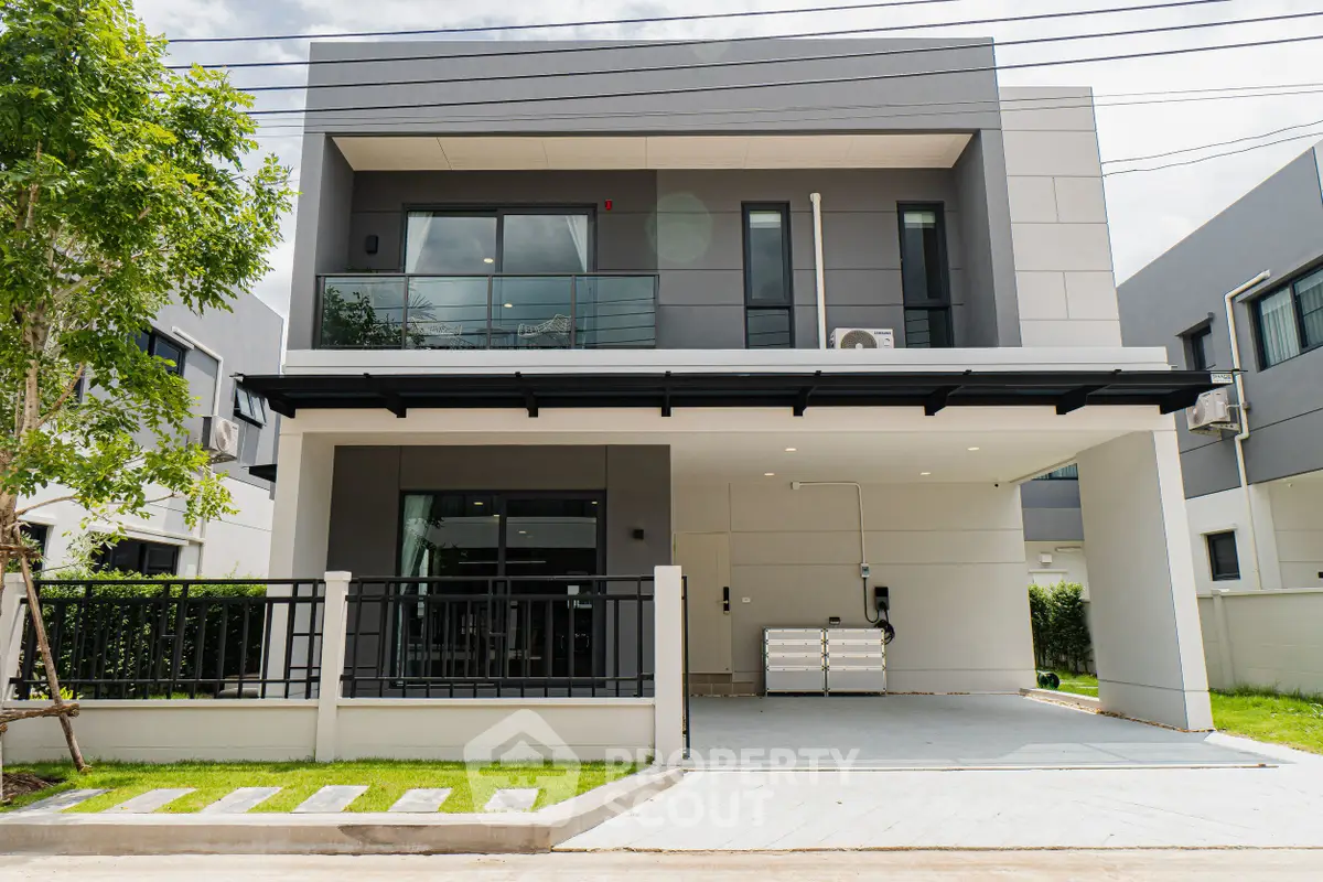 Modern two-story house with sleek design and spacious driveway in a suburban neighborhood.