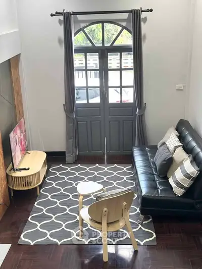 Charming living room with stylish decor and natural light, featuring a cozy sofa and modern TV setup.