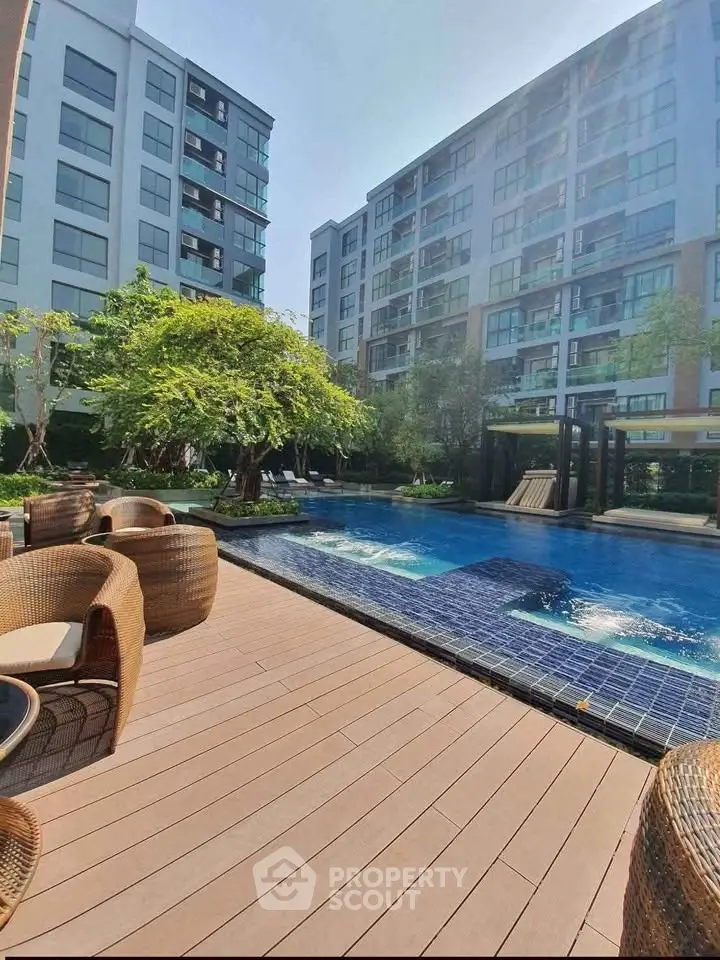 Luxurious apartment complex with poolside view and modern outdoor seating area.