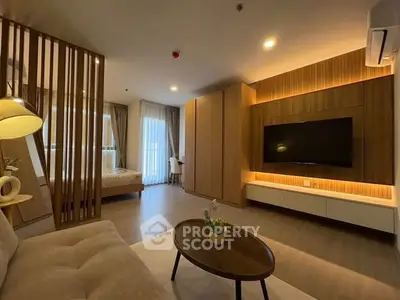 Modern living room with wooden accents and open layout leading to a cozy bedroom.