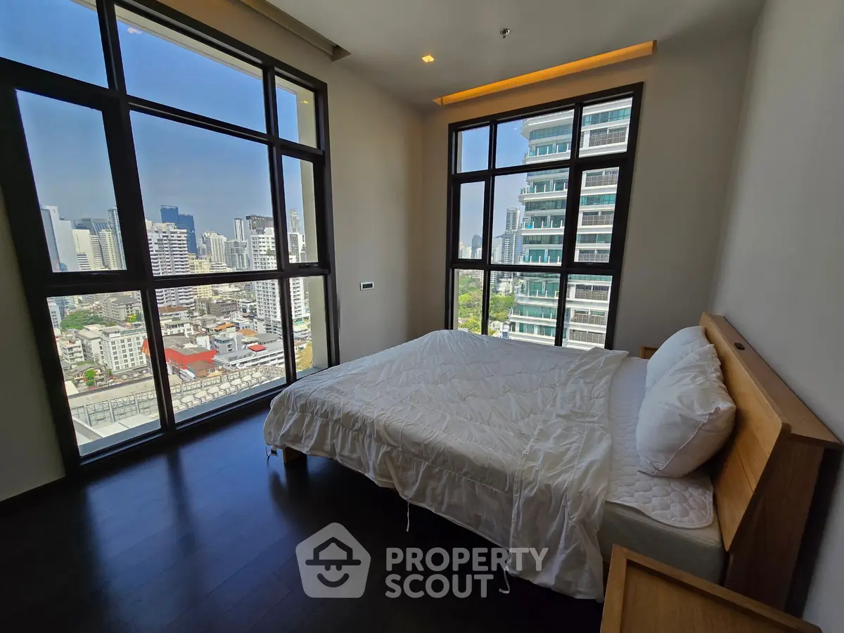Luxurious bedroom with stunning city view and floor-to-ceiling windows in modern high-rise apartment.