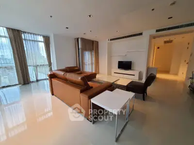 Spacious modern living room with leather sofa and large windows offering city views.