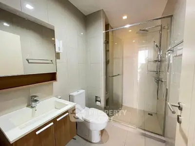 Modern bathroom with glass shower and sleek vanity in contemporary apartment.