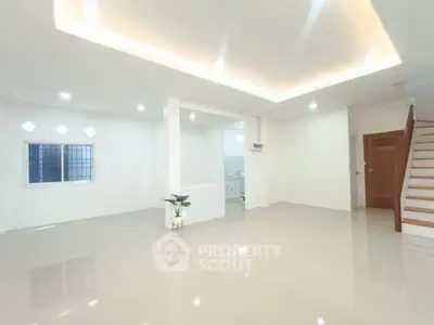 Spacious modern living room with glossy tile flooring and elegant staircase