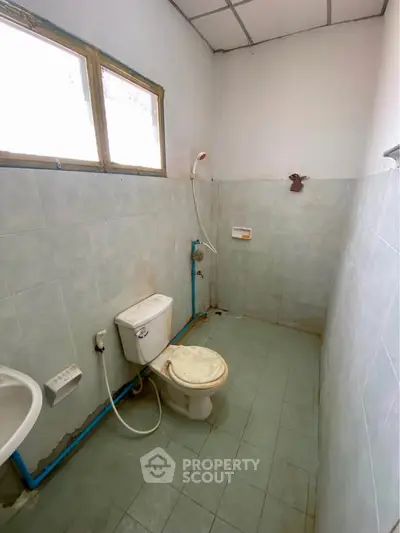 Basic bathroom with toilet and shower in need of renovation.