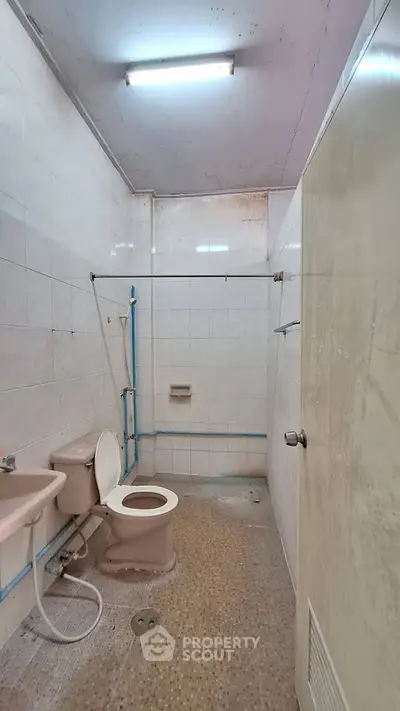 Modest bathroom with basic fixtures and tiled walls, ideal for renovation.