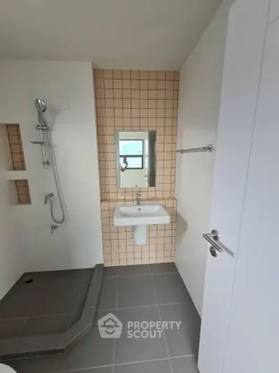 Modern bathroom with sleek design and neutral tones, featuring a shower and stylish tiles.
