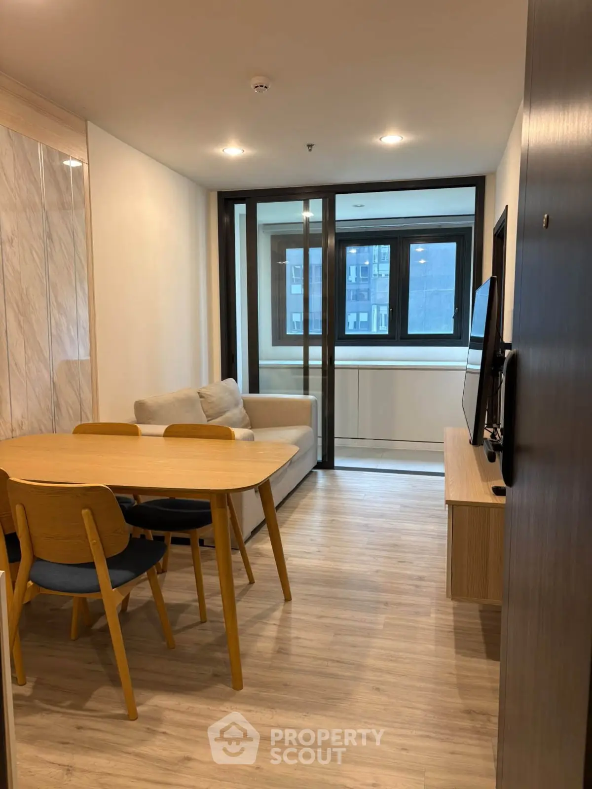 Modern living room with dining area and large window in a stylish apartment.