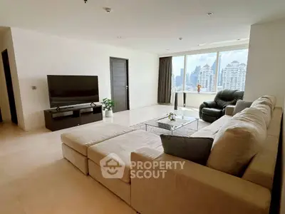 Spacious modern living room with city view, large sofa, and sleek TV setup.