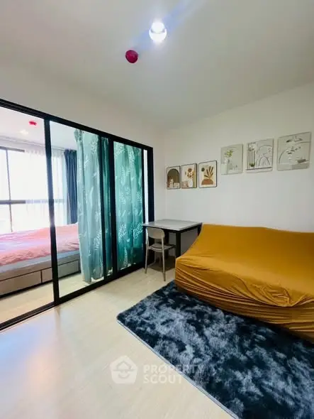 Modern apartment with cozy living area and stylish bedroom separated by glass doors.