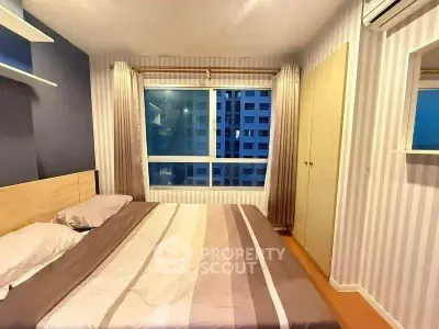Cozy bedroom with large window and modern decor in a high-rise apartment.