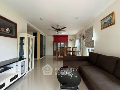 Spacious living room with modern decor and ceiling fan, perfect for family gatherings.