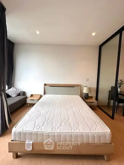 Spacious bedroom with modern decor and large window for natural light.