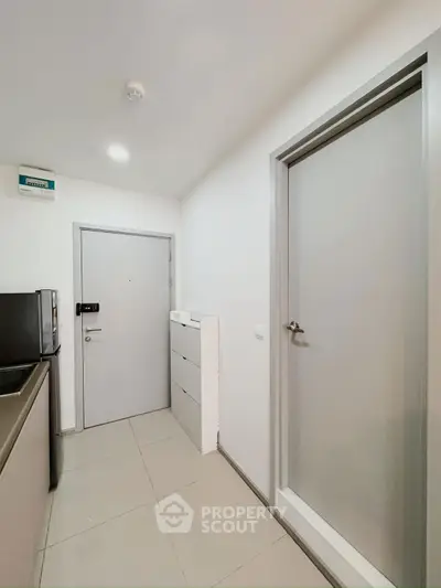 Modern apartment entryway with sleek kitchen appliances and minimalist design.
