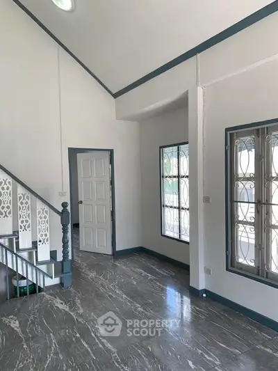 Spacious modern living room with elegant staircase and large windows