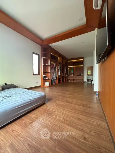 Spacious bedroom with wooden flooring and built-in closet, perfect for modern living.