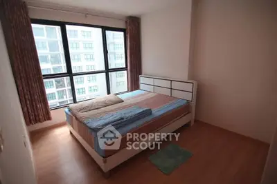 Cozy bedroom with large window and modern furnishings in urban apartment