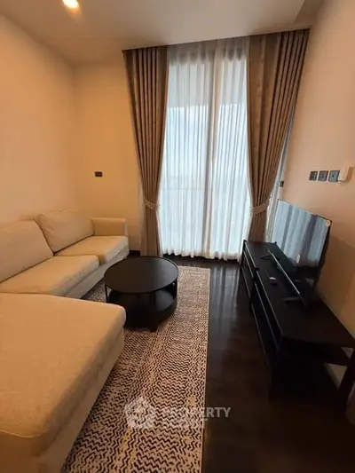 Modern living room with elegant beige sofa, stylish curtains, and sleek TV setup.