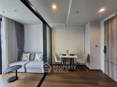 Modern living room with elegant dining area and glass partition, featuring stylish decor and cozy ambiance.