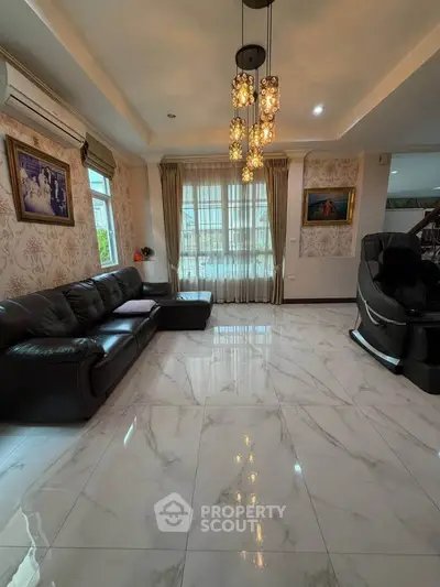 Luxurious living room with elegant chandelier and marble flooring, featuring a cozy leather sofa and large window.