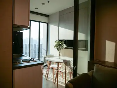 Modern kitchen with open layout and balcony view, featuring sleek cabinetry and dining area.